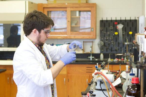 a man wearing gloves and a white coat working in a laboratory